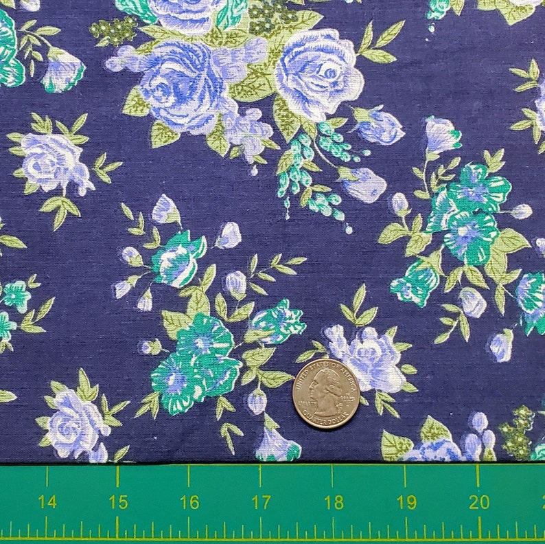 May include: A close-up of a navy blue fabric with a white and green floral pattern. A US quarter is included for scale.