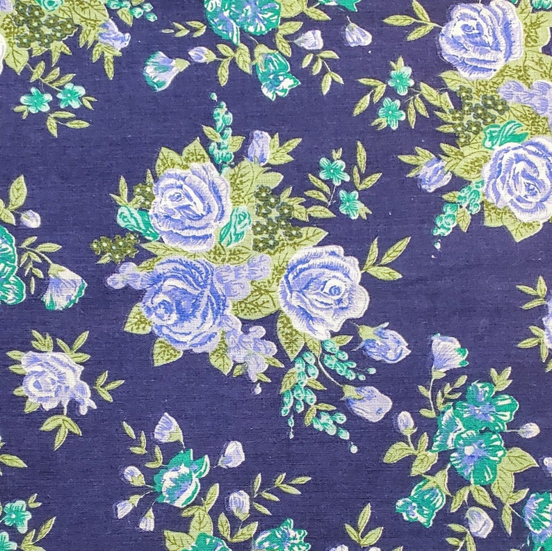 May include: A dark blue fabric with a repeating pattern of light blue roses and green leaves.