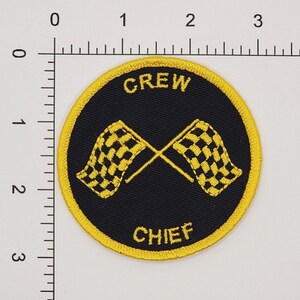 Pu&ograve; includere: Una toppa ricamata gialla e nera con le parole "CREW CHIEF" e due bandiere a scacchi incrociate.