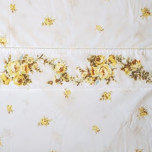 May include: White bedding with a yellow floral pattern. The floral pattern is a border along the bottom of the bedding.