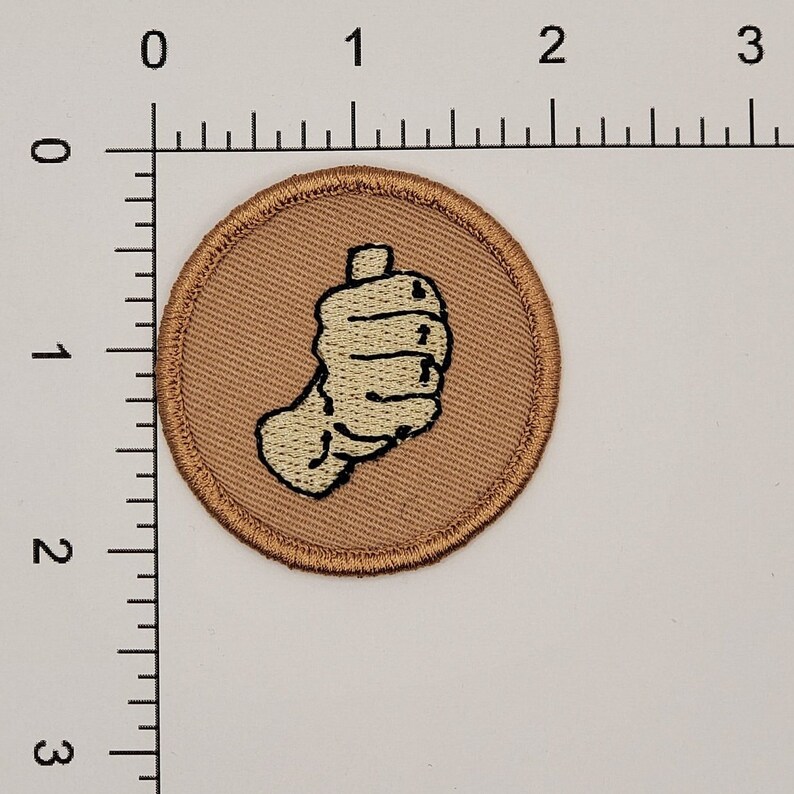 May include: A brown embroidered patch with a white hand giving a thumbs up.