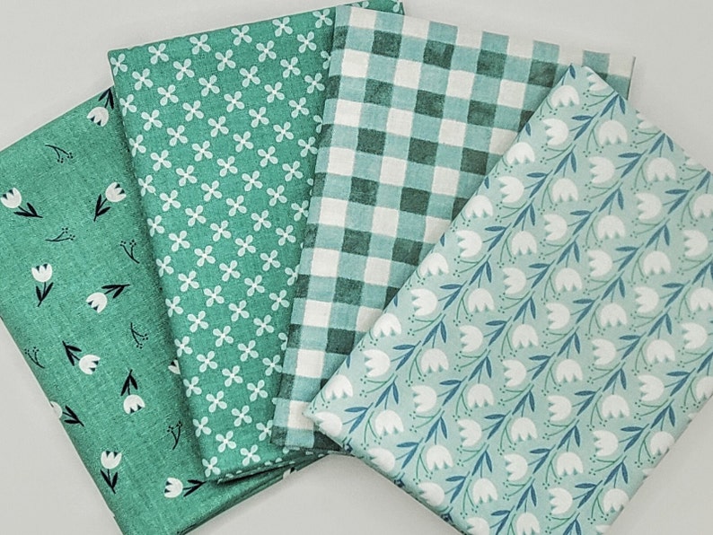 Pode incluir: Quatro amostras de tecido em tons de verde com padr&otilde;es diferentes. Uma tem um padr&atilde;o floral branco, outra tem um padr&atilde;o xadrez branco e verde, uma tem um pequeno padr&atilde;o de flores brancas e outra tem um padr&atilde;o de tulipas brancas.