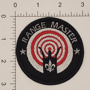 May include: Black and white embroidered patch with a red and white target in the centre. The text "RANGE MASTER" is written around the target in a white circle.