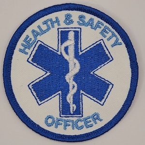 May include: A white embroidered patch with a blue star of life and the text "HEALTH & SAFETY OFFICER" in blue.