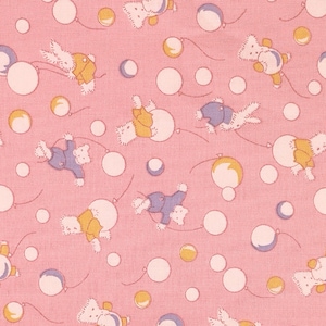 May include: A pink fabric with a repeating pattern of white and yellow circles and cartoon bears holding balloons. The bears are wearing blue, yellow, and pink clothing.