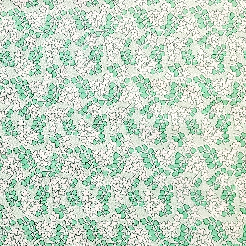 Pu&ograve; includere: Uno schema senza cuciture con fiori bianchi e foglie verdi su uno sfondo bianco. Lo schema si ripete in tutta l'immagine.