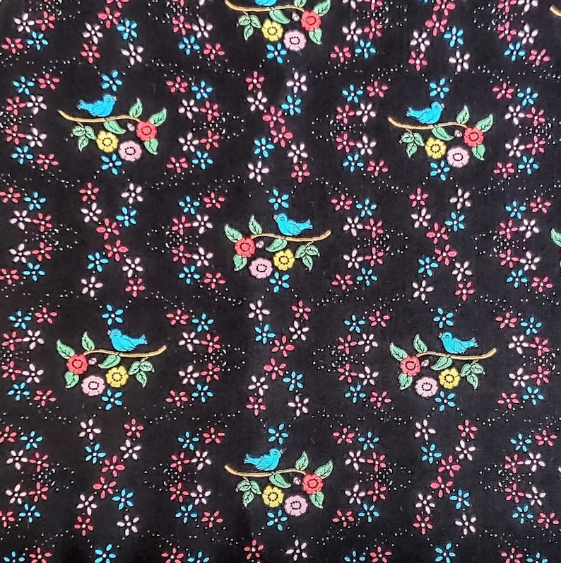 May include: Black fabric with a repeating pattern of blue birds, pink, yellow, and white flowers, and small white dots.