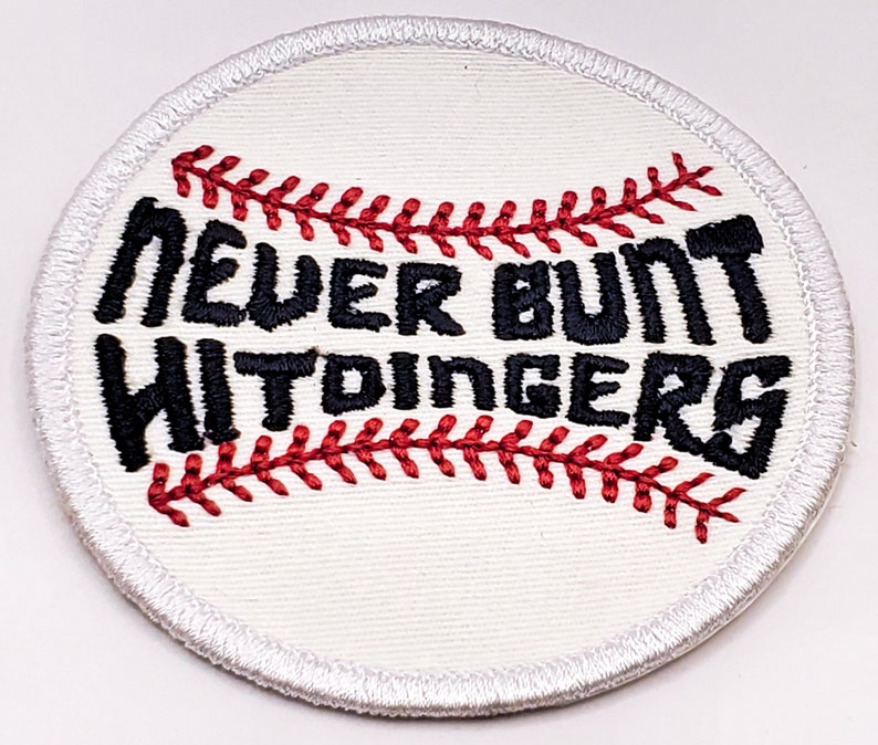 May include: White embroidered baseball patch with red stitching and the text "Never Bunt Hittingers" in black.