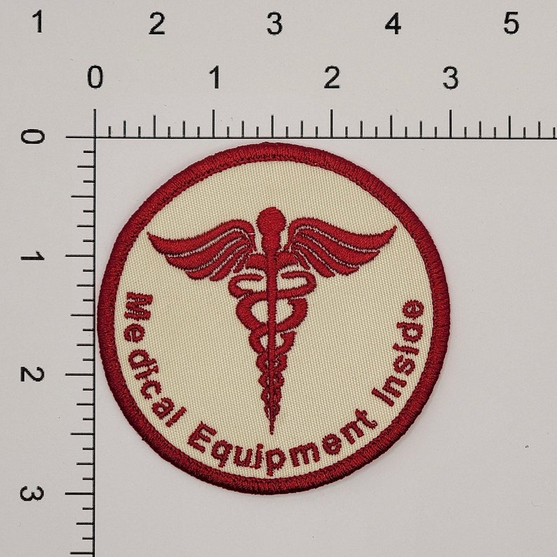 以下が含まれることがあります： 赤と白の丸いパッチで、赤い医療シンボルと「Medical Equipment Inside」の文字が書かれています。