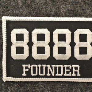 May include: Black rectangular patch with white embroidered numbers "8888" and the word "FOUNDER". The patch has a white border and is set against a gray textured background.