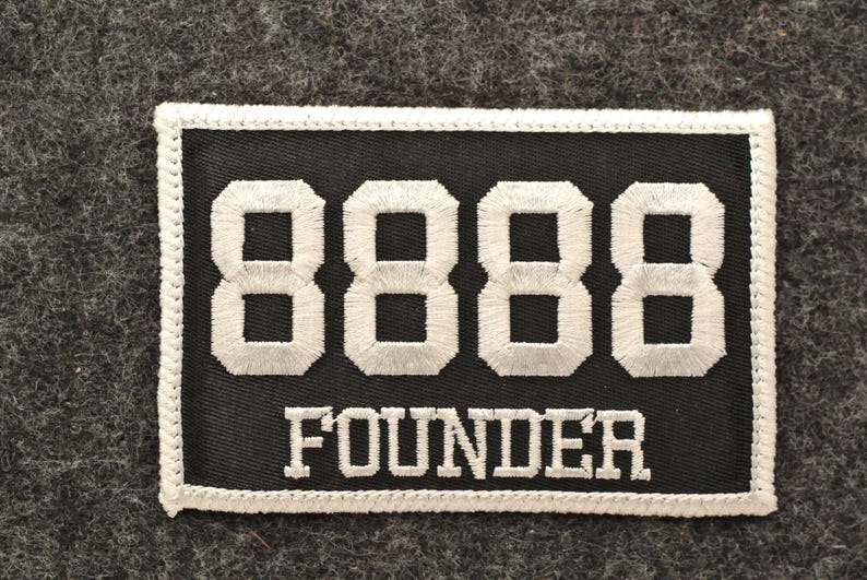 May include: Black rectangular patch with white embroidered numbers "8888" and the word "FOUNDER". The patch has a white border and is set against a gray textured background.
