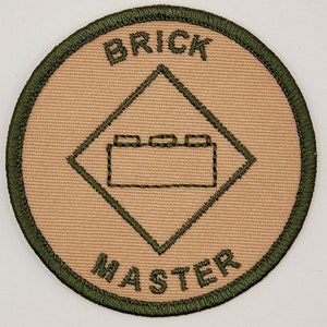 May include: A tan and green embroidered patch with the words "Brick Master" and a graphic of a Lego brick.