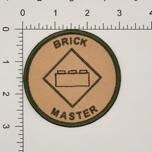 May include: A tan and green round patch with the text "BRICK MASTER" and a diamond shape with a brick outline in the center.