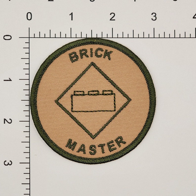 May include: A tan and green round patch with the text "BRICK MASTER" and a diamond shape with a brick outline in the center.