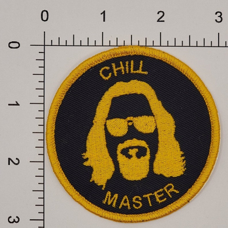 May include: A round, black and gold embroidered patch with the text "CHILL MASTER" and a silhouette of a man with a beard and sunglasses.