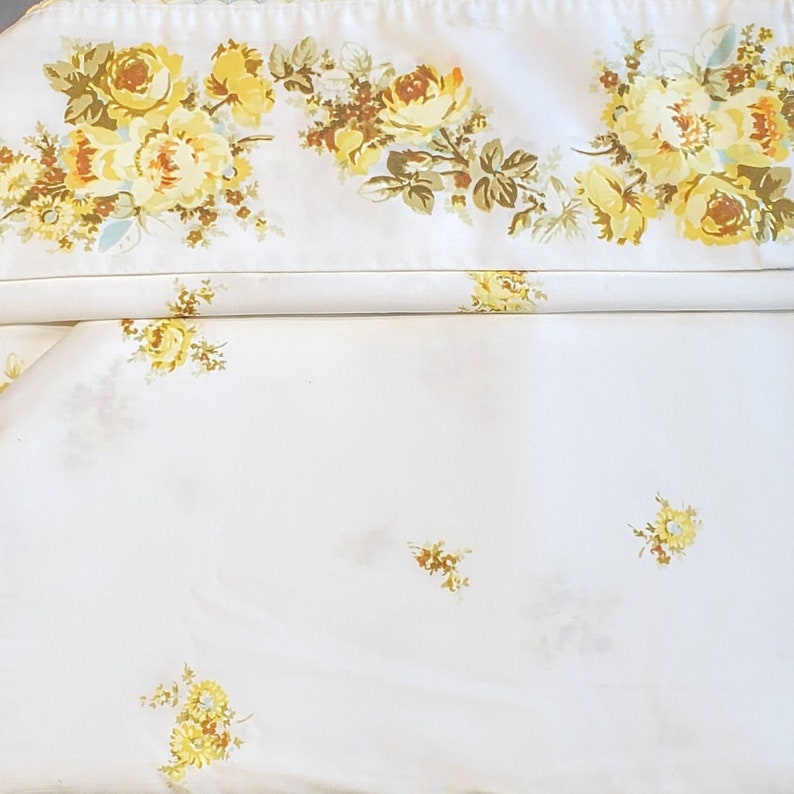 May include: White fabric with a yellow floral pattern. The fabric has a subtle sheen and a delicate floral design.