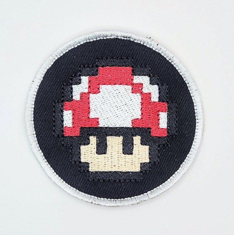 以下が含まれることがあります： 赤と白のスーパーマリオのキノコが刺繍された黒と白のパッチ