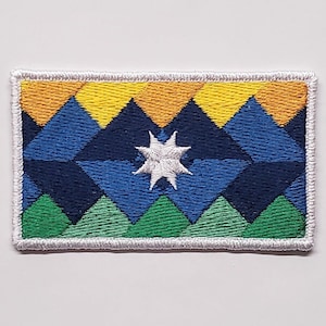 May include: An embroidered patch with a geometric design featuring a white star in the center. The design is made up of yellow, orange, blue, green, and white triangles.