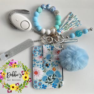 Estampado floral, llaveros de seguridad, defensa, pulsera con cuentas, accesorios, billetera, alarma con luz led, silbato, agarrador de tarjetas, etc., varios colores