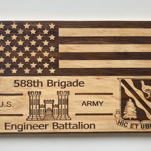 May include: A wooden plaque with an American flag, the text "588th Brigade U.S. Army Engineer Battalion", and a crest with a bird and a tree. The plaque is made of light and dark wood.