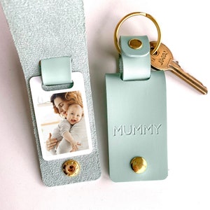 May include: A light blue leather keychain with a photo insert and the word "MUMMY" embossed on the front. The keychain has a gold ring and a gold key attached.