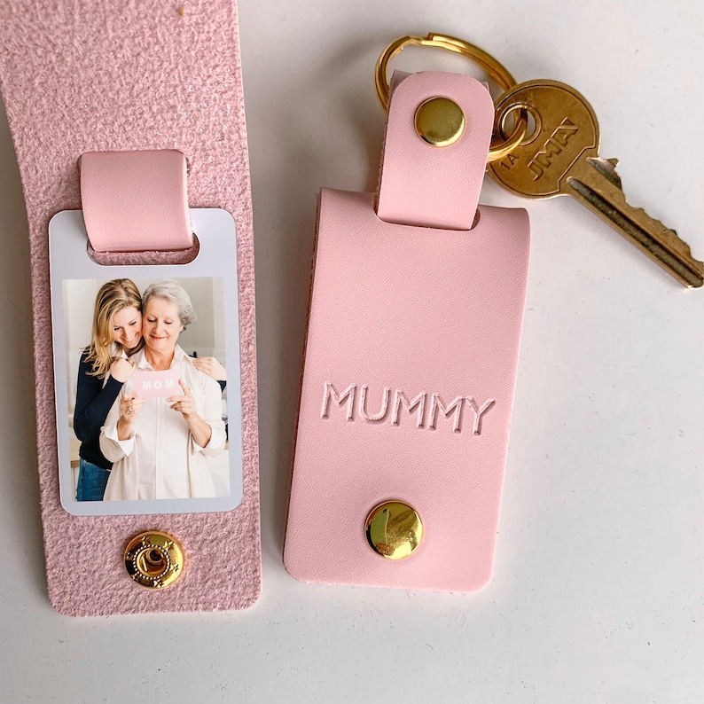 May include: Pink leather keychain with a photo insert and the word "MUMMY" embossed on the front. The keychain has a gold metal ring and a gold key.