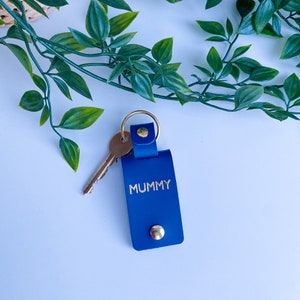 May include: A blue leather keychain with a gold key ring and the word "MUMMY" in gold lettering.