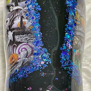 May include: A black tumbler with a glittery blue and purple design. The tumbler features a black and white image of a spooky Halloween scene.