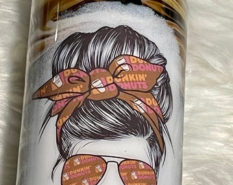 May include: A white tumbler with a brown marble design. The tumbler features a cartoon illustration of a woman with a messy bun, wearing sunglasses and a brown bandana with a Dunkin' Donuts pattern. The text "#DUNKINDONUTSLIFE" is printed on the bottom of the tumbler.