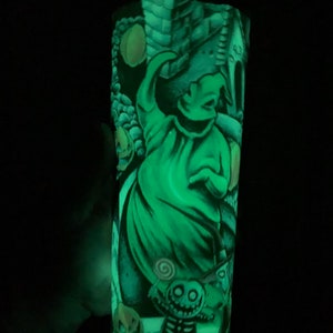 May include: A green glow-in-the-dark tumbler with a graphic of Jack Skellington from The Nightmare Before Christmas. The design includes Jack Skellington, Oogie Boogie, and other characters from the movie.
