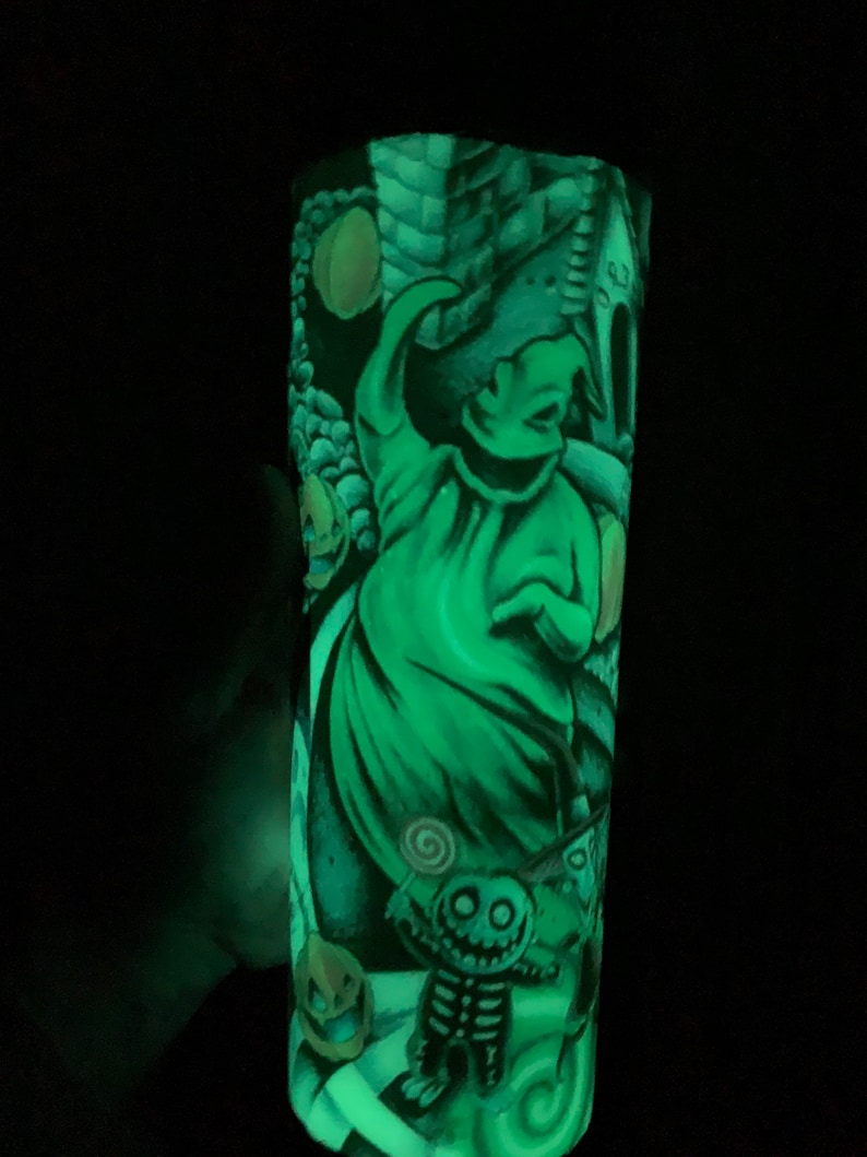 May include: A green glow-in-the-dark tumbler with a graphic of Jack Skellington from The Nightmare Before Christmas. The design includes Jack Skellington, Oogie Boogie, and other characters from the movie.