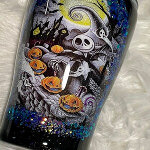May include: Black and white tumbler with a glittery blue and black finish. The tumbler features a graphic of Jack Skellington from The Nightmare Before Christmas with pumpkins and bats.