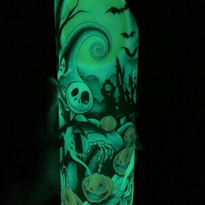 May include: A glow-in-the-dark Halloween-themed tumbler with a black and white illustration of Jack Skellington from The Nightmare Before Christmas. The illustration includes a spooky house, a crescent moon, bats, and pumpkins.