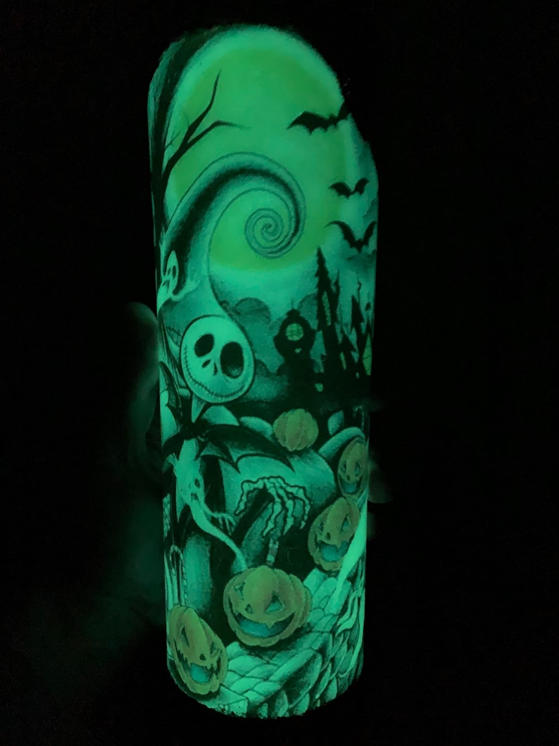 May include: A glow-in-the-dark Halloween-themed tumbler with a black and white illustration of Jack Skellington from The Nightmare Before Christmas. The illustration includes a spooky house, a crescent moon, bats, and pumpkins.