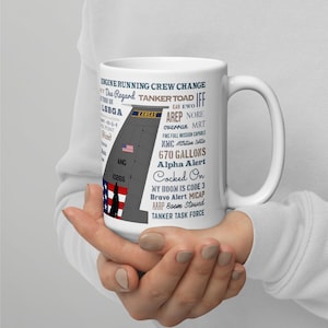 Może przedstawiać: Biały ceramiczny kubek z napisem "ENGINE RUNNING CREW CHANGE" i "TANKER TOAD". Na kubku widnieje również napis "KANSAS" i flaga amerykańska. Kubek mieści 2536.05 litrów.