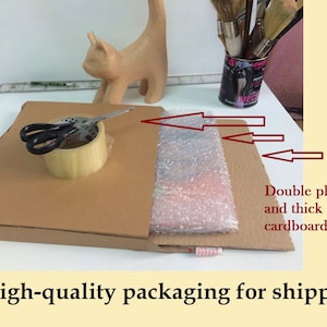 May include: A cardboard box with bubble wrap and tape, ready for shipping. Scissors and a roll of tape sit on top of the box. The packaging is designed to protect the contents during transit.