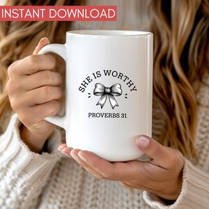 Op de afbeelding: Witte keramische mok met een zwart ontwerp met de tekst "She is Worthy" met een strik en "Proverbs 31".
