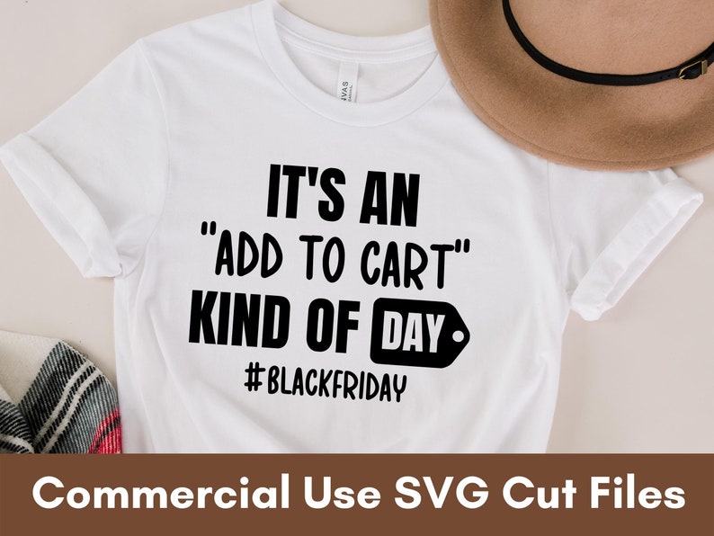 Puede incluir: Camiseta blanca con el texto "IT'S AN 'ADD TO CART' KIND OF DAY" en negro. El hashtag #BLACKFRIDAY est&aacute; debajo del texto. Un sombrero marr&oacute;n est&aacute; en el fondo. Archivos de corte SVG de uso comercial.