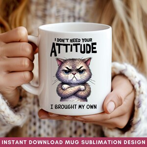 Op de afbeelding: Een witte keramische mok met een cartoonkat met gekruiste armen en een boze uitdrukking. Op de mok staat "I don't need your attitude I brought my own".