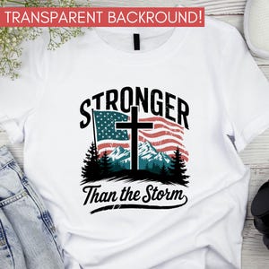 May include: White t-shirt with a graphic design featuring a cross over an American flag with mountains in the background. The text "Stronger Than the Storm" is below the graphic.