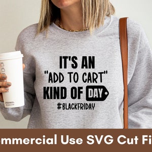 Puede incluir: Una sudadera gris claro con el texto "IT'S AN 'ADD TO CART' KIND OF DAY #BLACKFRIDAY" en negro. Una taza de caf&eacute; blanca se sostiene en la mano izquierda. Las palabras "Commercial Use SVG Cut Files" est&aacute;n en la parte inferior.