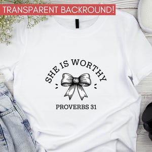 Op de afbeelding: Wit T-shirt met zwarte tekst die "She is Worthy" luidt met een zwarte strik en "Proverbs 31" eronder.