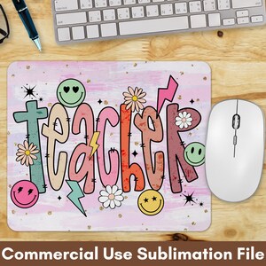May include: A pink and white mouse pad with the word "teacher" written in colorful, stylized letters. The letters are decorated with flowers, stars, and smiley faces. The mouse pad is designed for sublimation printing.