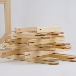 May include: A stack of wooden canvas stretcher bars, ready to be assembled into a frame for a painting or artwork.
