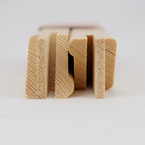 May include: Close-up of the edge of a wooden canvas frame. The frame is made of natural wood with a light brown color. The wood has a visible grain pattern.