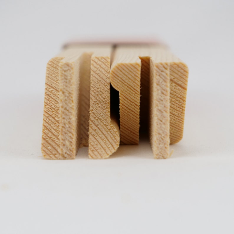 May include: Close-up of the edge of a wooden canvas frame. The frame is made of natural wood with a light brown color. The wood has a visible grain pattern.