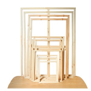 May include: A set of seven wooden canvas frames in various sizes, stacked and arranged in descending order from largest to smallest. The frames are made of natural, unpainted wood.