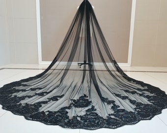 May include: A black tulle wedding veil with a beaded lace trim. The veil is long and flowing, with a scalloped edge.