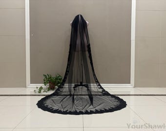 May include: A long, black bridal veil with a delicate lace trim. The veil is displayed on a mannequin, showcasing its full length and intricate design. The lace detailing adds a touch of elegance to the sheer fabric.