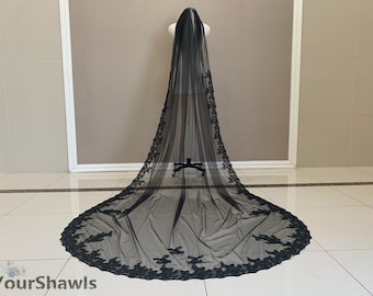 May include: A black tulle wedding veil with a floral lace trim. The veil is long and flowing, and the lace trim is delicate and intricate.